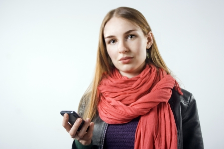 young blonde girl with a mobile phone in his hand on a light backgroundの写真素材