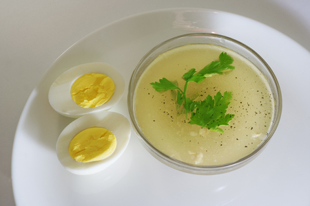 in a glass bowl of broth with egg and parsleyの写真素材
