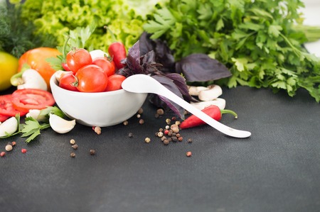 fresh tomatoes, basil, other greens in white bowl on black backgの写真素材