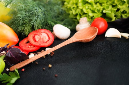 Fresh sliced vegetables and a wooden spoon on a dark background. Healthy, balanced dietの写真素材