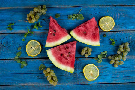 pieces of ripe watermelon, lemon, grapes and mint on the backgroの写真素材