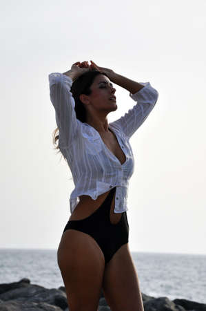 Young beautiful woman on the beach rocks at sunsetの写真素材
