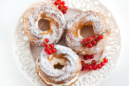 Cream puff rings (choux pastry) decorated with fresh red currant