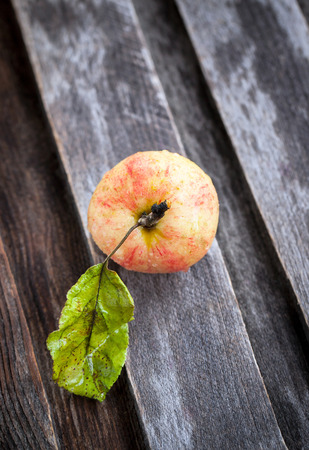 Wet fresh red apple on the fallen leaves on wooden tableの写真素材