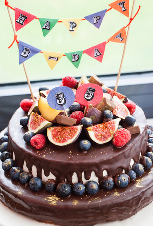 Homemade chocolate frosted cake decorated with fresh fruitの写真素材