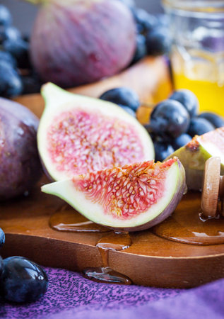 Fresh figs and dark grape with honey on tableの写真素材