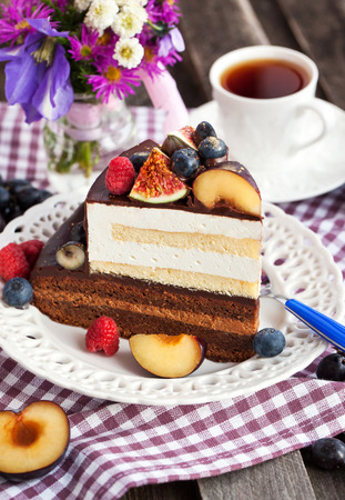 Piece of chocolate layer cake with cream and fresh fruitの写真素材