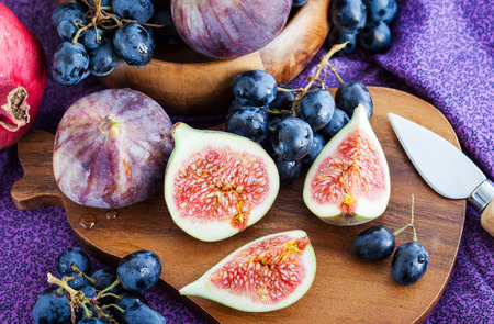Fresh figs and dark grape with honey on table