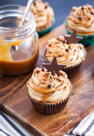 Cupcakes decorated with cream cheese, caramel sauce and chocolateの写真素材