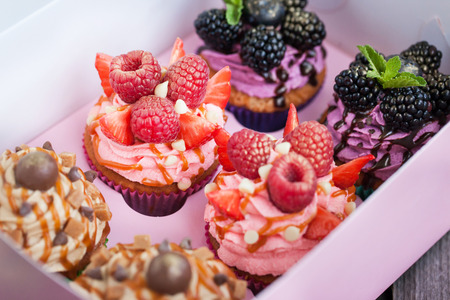 Set of different delicious cupcakes  in a pink paper box, selective focusの写真素材