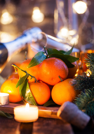 Holiday concept: fresh tangerines, cork, glass, champagne, candles and garlandsの写真素材