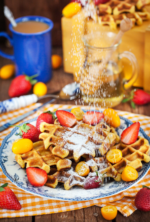Belgian pumpkin waffles with fresh strawberry, kumquat, honey and cup of coffeeの写真素材