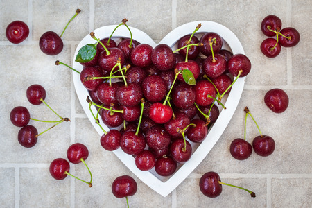 Fresh wet summer cherry in heart shaped bowlの写真素材