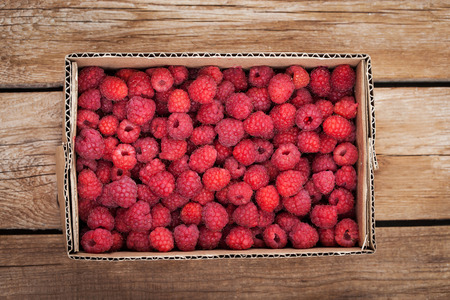 Fresh organic ripe raspberry in box on wooden table