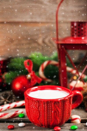 Christmas time red cup of milk and latern with candle light, holiday decorations around, copy spaceの写真素材
