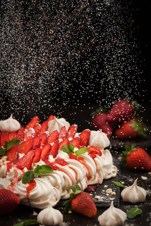 Delicious Pavlova meringue cake decorated with fresh strawberry on black backgroundの写真素材