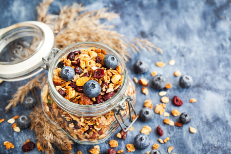 Homemade granola in jar and fresh blueberry, healthy breakfast of oatmeal muesli, nuts, seeds and dried fruitの写真素材