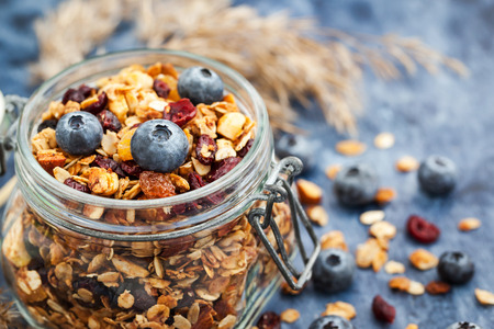 Homemade granola in jar and fresh blueberry, healthy breakfast of oatmeal muesli, nuts, seeds and dried fruitの写真素材