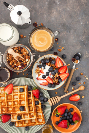 Healthy breakfast table with cereal granola, milk, fresh berries, coffee and waffles, top view
の写真素材