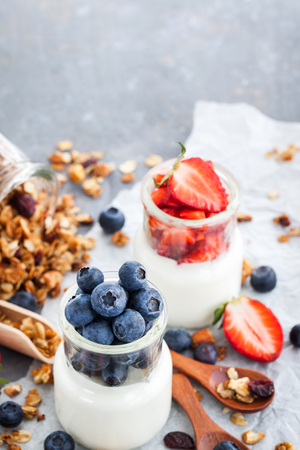 Delicious plain yogurt with fresh blueberry and strawberry in a glass jars for breakfastの写真素材