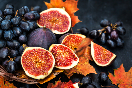Autumnal fresh ripe figs and purple grape on dark  backgroundの写真素材