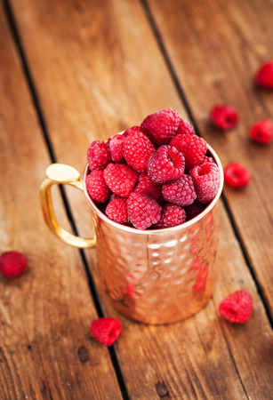 Fresh ripe raspberries in a copper mugの写真素材