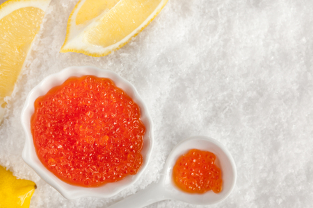 Delicious red caviar in bowl on white snow background, top viewの写真素材