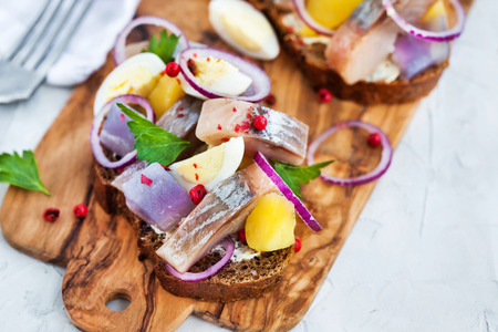 Open sandwich (smorrebrod) with herring, onion, potato and eggsの写真素材