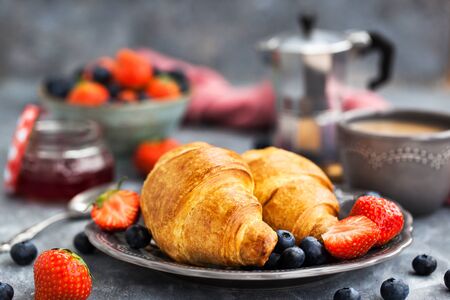 Continental breakfast with croissants, fresh berries, coffee and jam, gray backgroundの写真素材