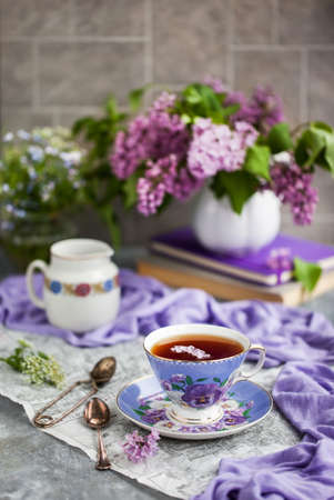 Purple cup of tae and lilac on gray backgroundの写真素材