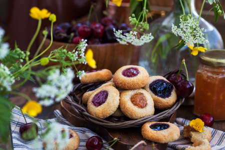 Thumbprint almond cookies with jam on rustic wooden background