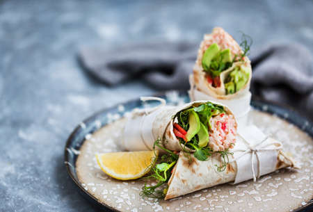 Fresh and healthy wrapped tortilla with crab salad, cucumber, avocado, pepper and green herbsの写真素材