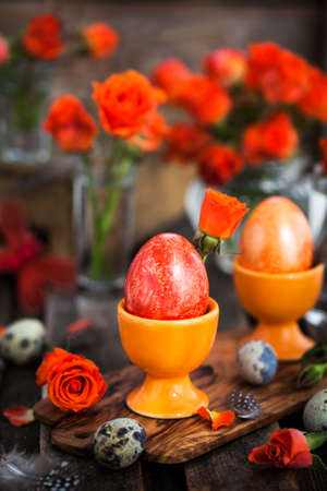 Easter colorful painted orange eggs and roses, spring holiday concept