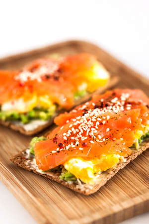 Salted salmon, scrambled eggs, avocado and cream cheese rye crisp toastの写真素材