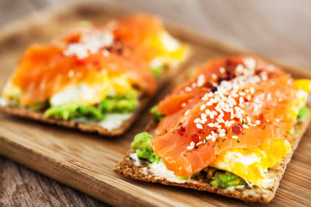 Salted salmon, scrambled eggs, avocado and cream cheese rye crisp toastの写真素材