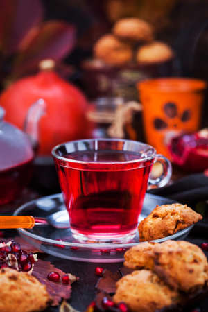 Glass cup of hot red tea and fresh homemade delicious apple cookies on rustic autumn backgroundの写真素材