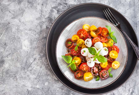 Fresh red and yellow cherry tomato salad with baby mozzarella cheese and basil, close-upの写真素材