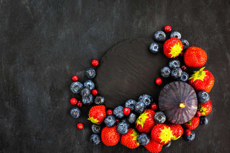 Fresh strawberries, blueberries and figs, on dark background, top viewの写真素材