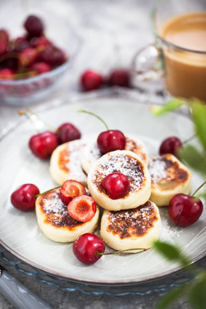 Cottage cheese pancakes with fresh cherry and coffee for breakfastの写真素材