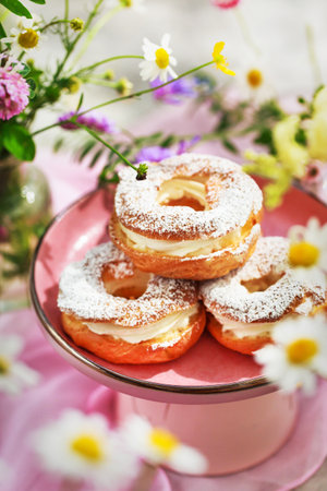 Delicious cream puff rings (choux pastry) with summer flowers aroundの写真素材