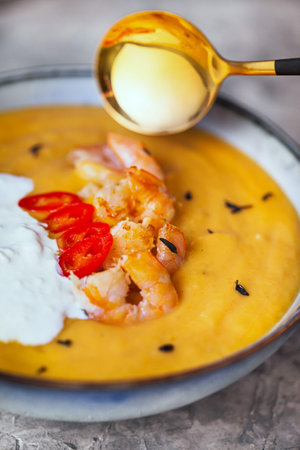 Delicious fresh cooking hot pumpkin and sweet potato soup, served with prawns, chili and...
