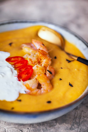 Delicious fresh cooking hot pumpkin and sweet potato soup, served with prawns, chili and stracciatella cheeseの写真素材