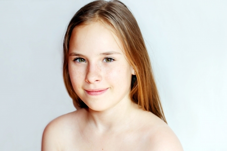 Portrait of a beautiful teenager girl with long hairs - over light grey backgroundの写真素材