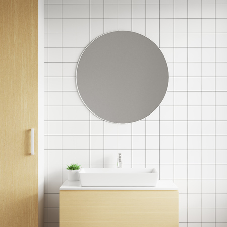 Close up white sink standing on a wooden shelf, with round mirror hanging on a white wallの写真素材