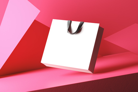 White bag with black handles isolated on a red background consisting of triangles.の写真素材