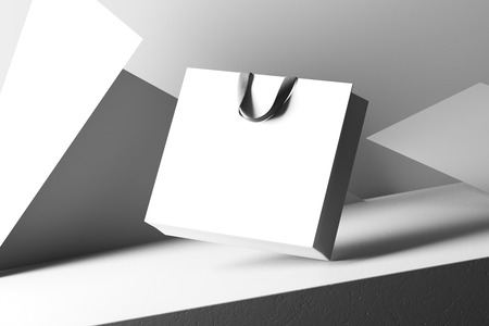 White shopping bag with black handles isolated on a white geometric background.の写真素材