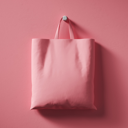 A pink textile shopping bag hangs in the center of the wall.の写真素材