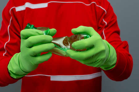 Man holding crushed plastic bottles in his hands in green gloves. Zero waste ecological lifestyle.
