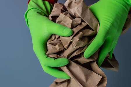 abstract photo of human hands in green gloves holding craft paper ball