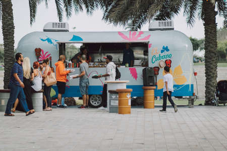 People walking at the park. Kids play and adults go around in the fair with green grass, palms,...